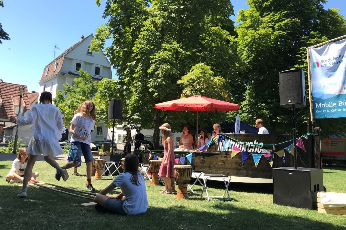 Auf dem schwarzen Holzboot "Kulturarche" steht eine Sängerin am Mikrofon. Davor sitzen zwei junge Männer in Liegestühlen.