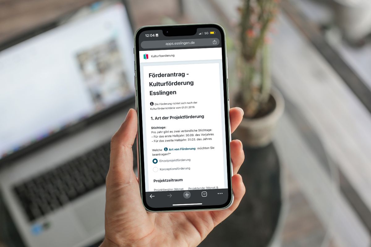 Hand hält Smartphone, auf dem das Online-Antragsformular für die Kulturförderung der Stadt Esslingen zu lesen ist