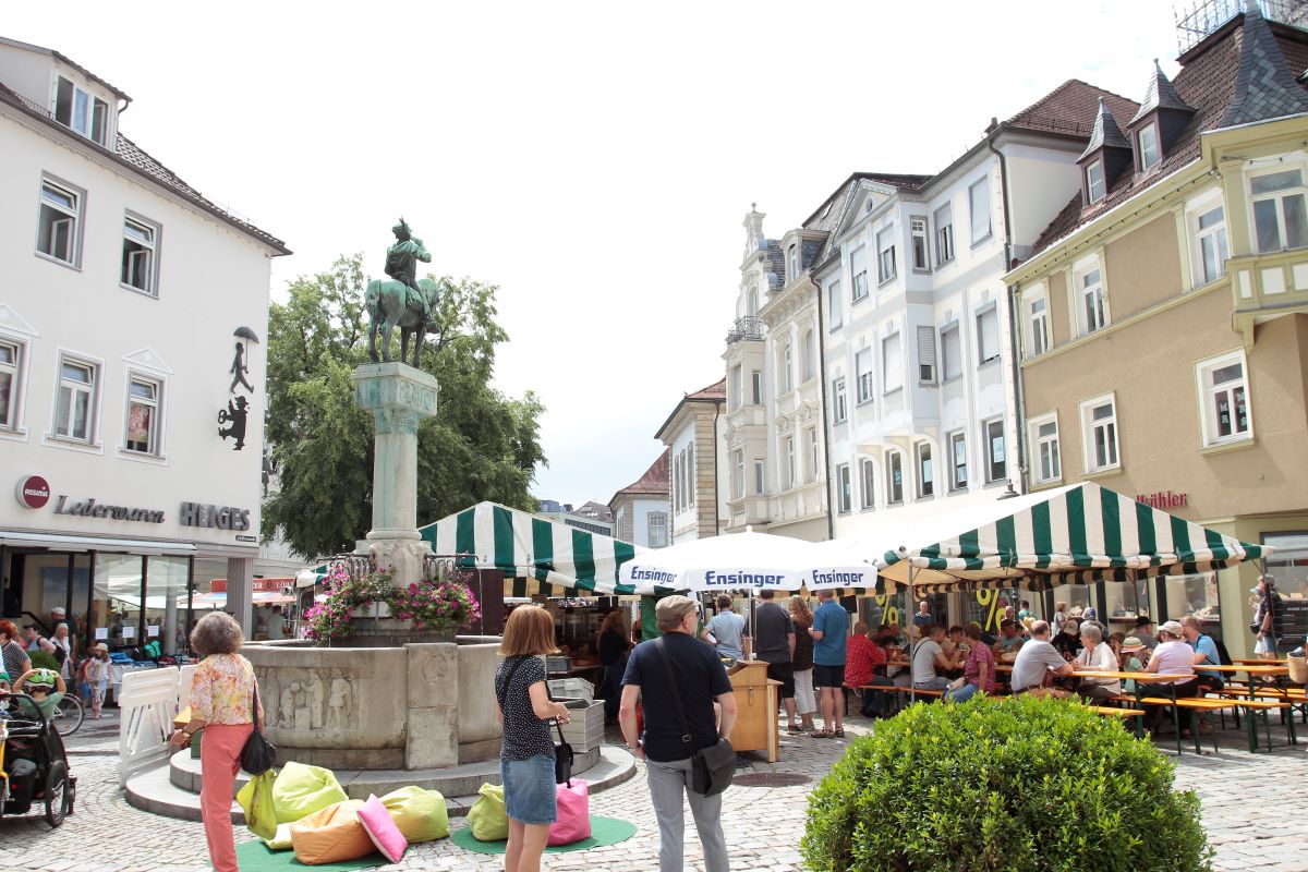 Buden, Zelte, Menschen und Sitzsäcke rund um den Postmichelbrunnen