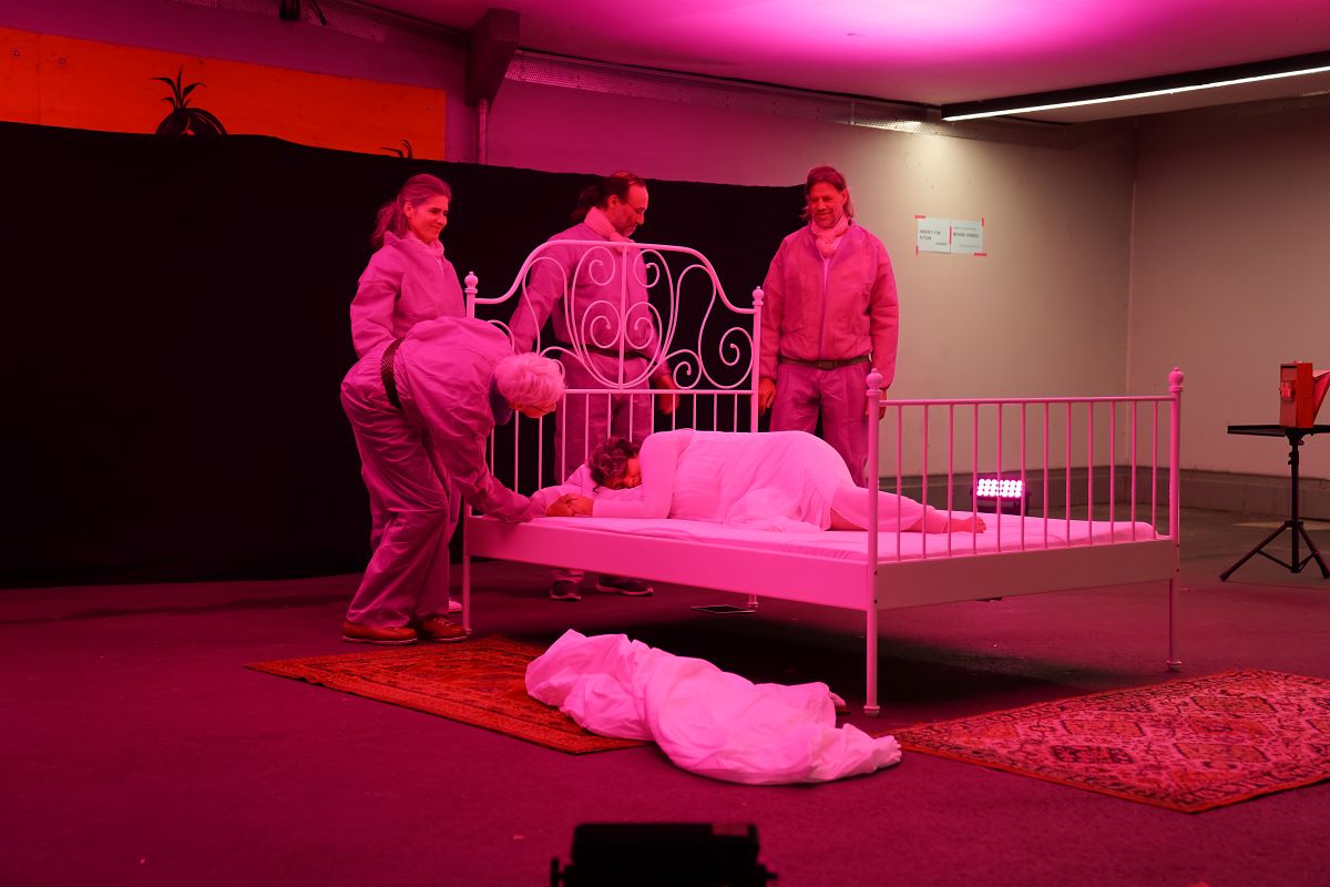 Obertongesang © Daniela Wolf vier Personen stehen um ein Bett, das rosarot beleuchtet ist