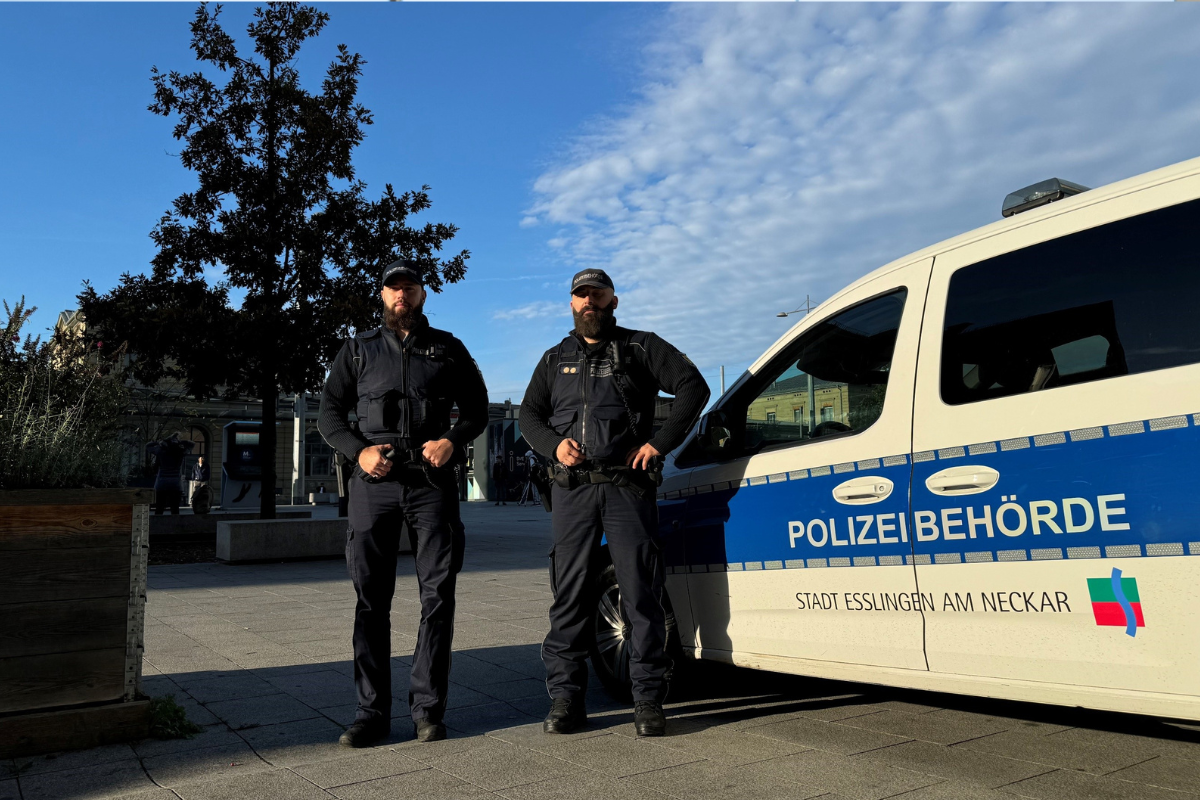 Zu sehen sind zwei Mitarbeitende des Kommunalen Ordnungsdienstes mit ihrem Fahrzeug auf dem Bahnhofplatz