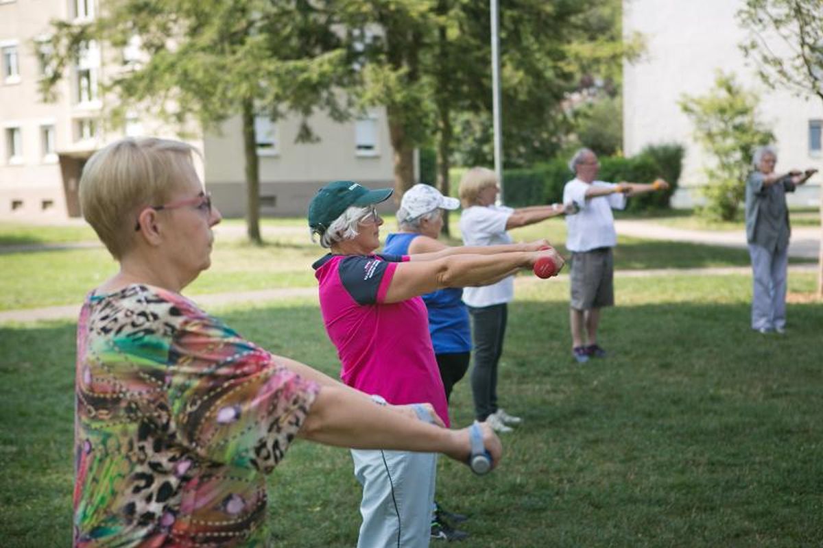 Senior:innen machen Gymnastik mit Gewichten im Park