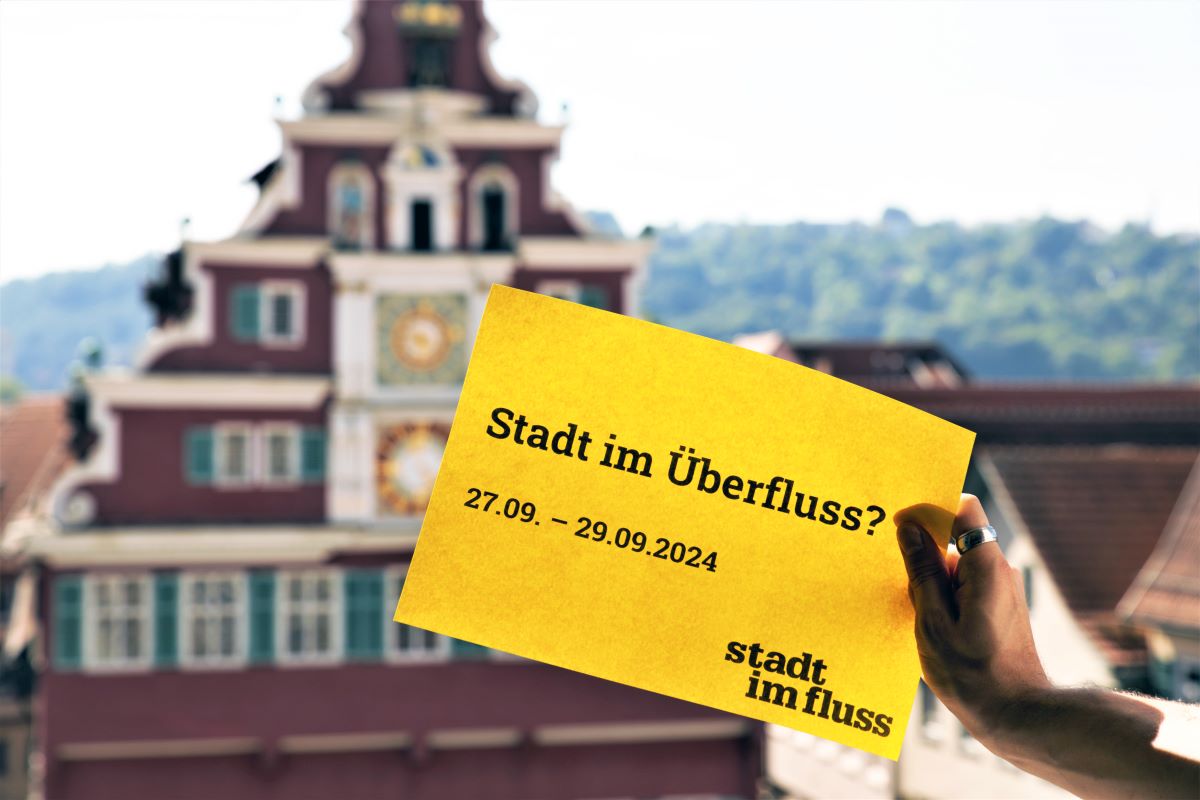 gelber Zettel mit Text Stadt im Überfluss? 27.09.-29.09.2024 Stadt im Fluss vor dem Hintergrund des Alten Rathauses Esslingen