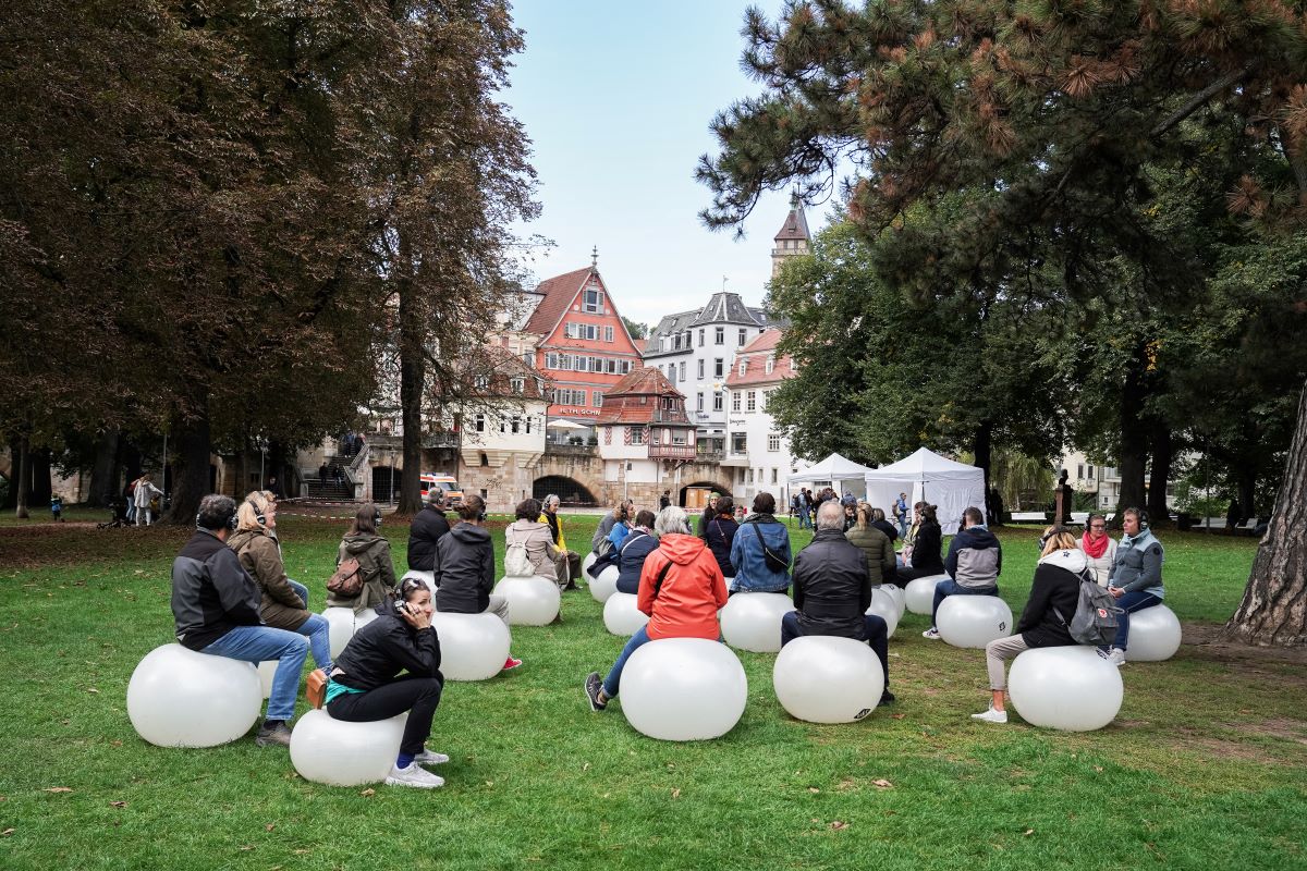 Menschen sitzen auf weißen Gymnastikbällen in einem Park