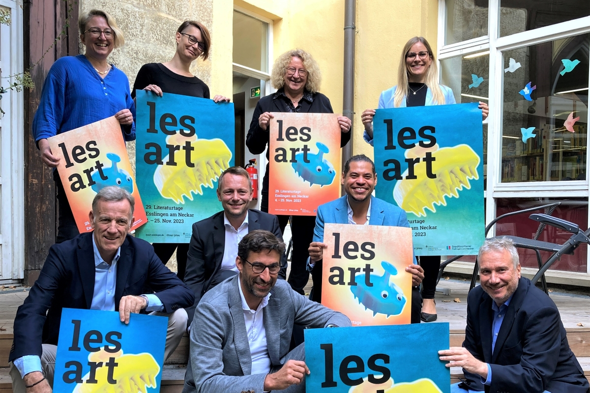 vier Damen und fünf Herren mit bunten lesart-Plakaten und einem strahlenden Lächeln im Gesicht