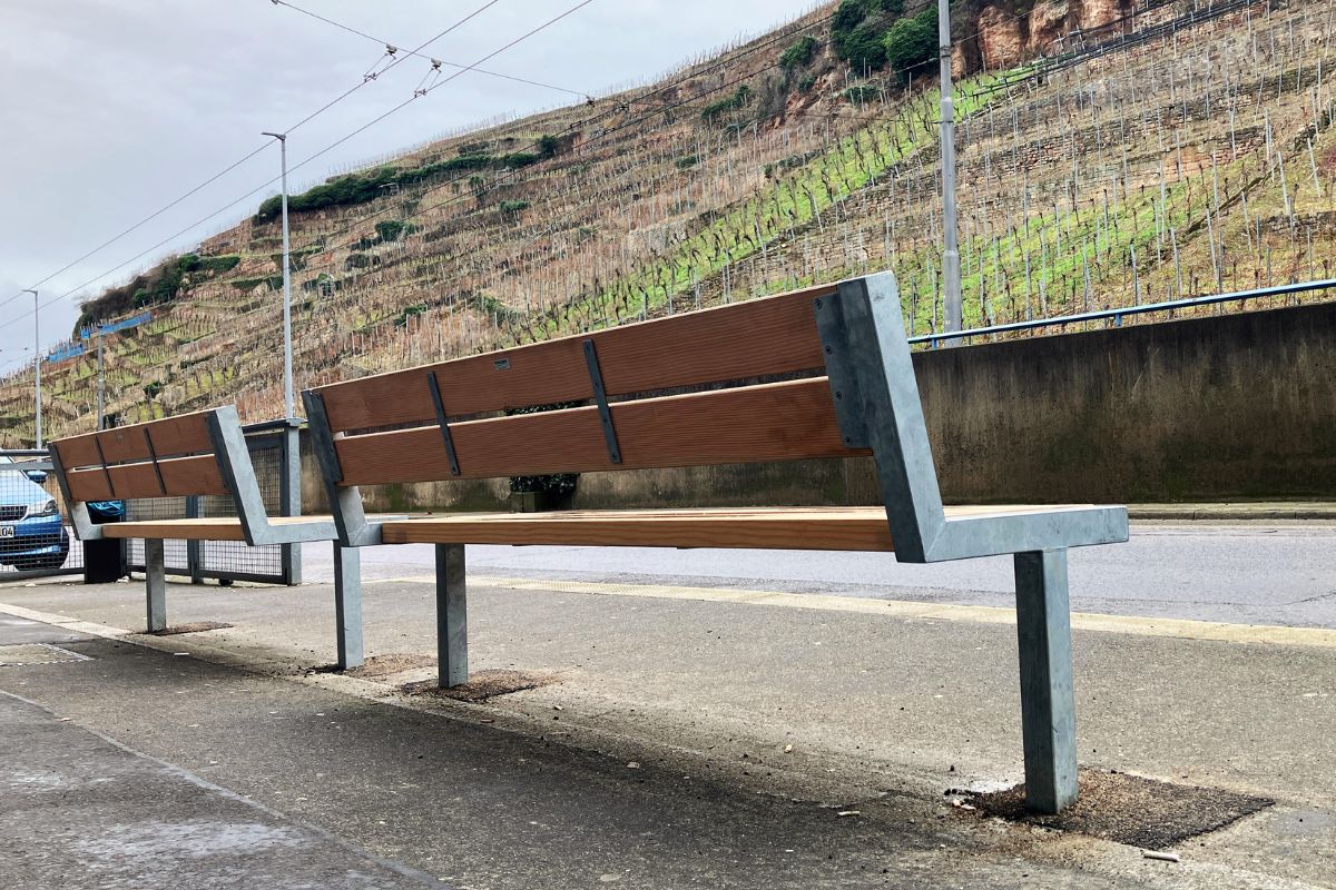 Zwei Sitzbänke aus Holz vor dem VHS-Gebäude in der Mettinger Straße, im Hintergrund die Weinberge