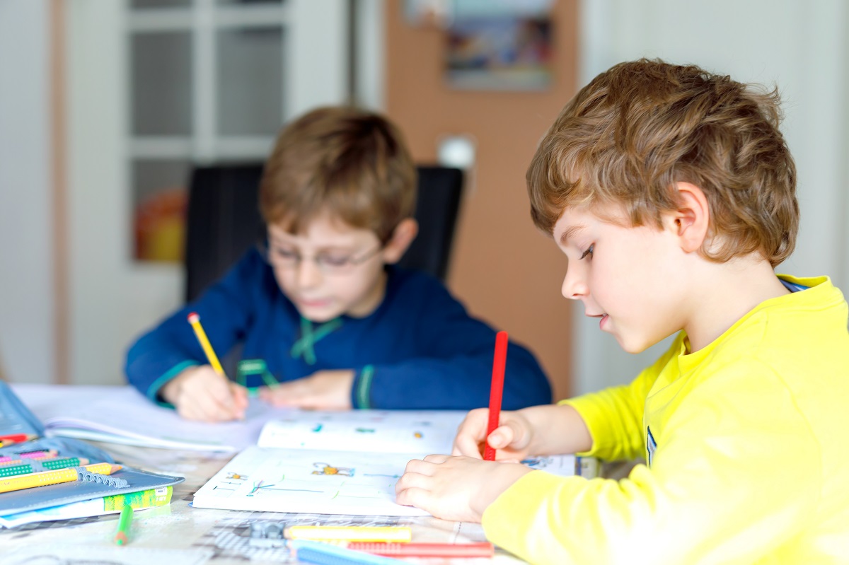 Kinder sitzen am Tisch und machen Hausaufgaben