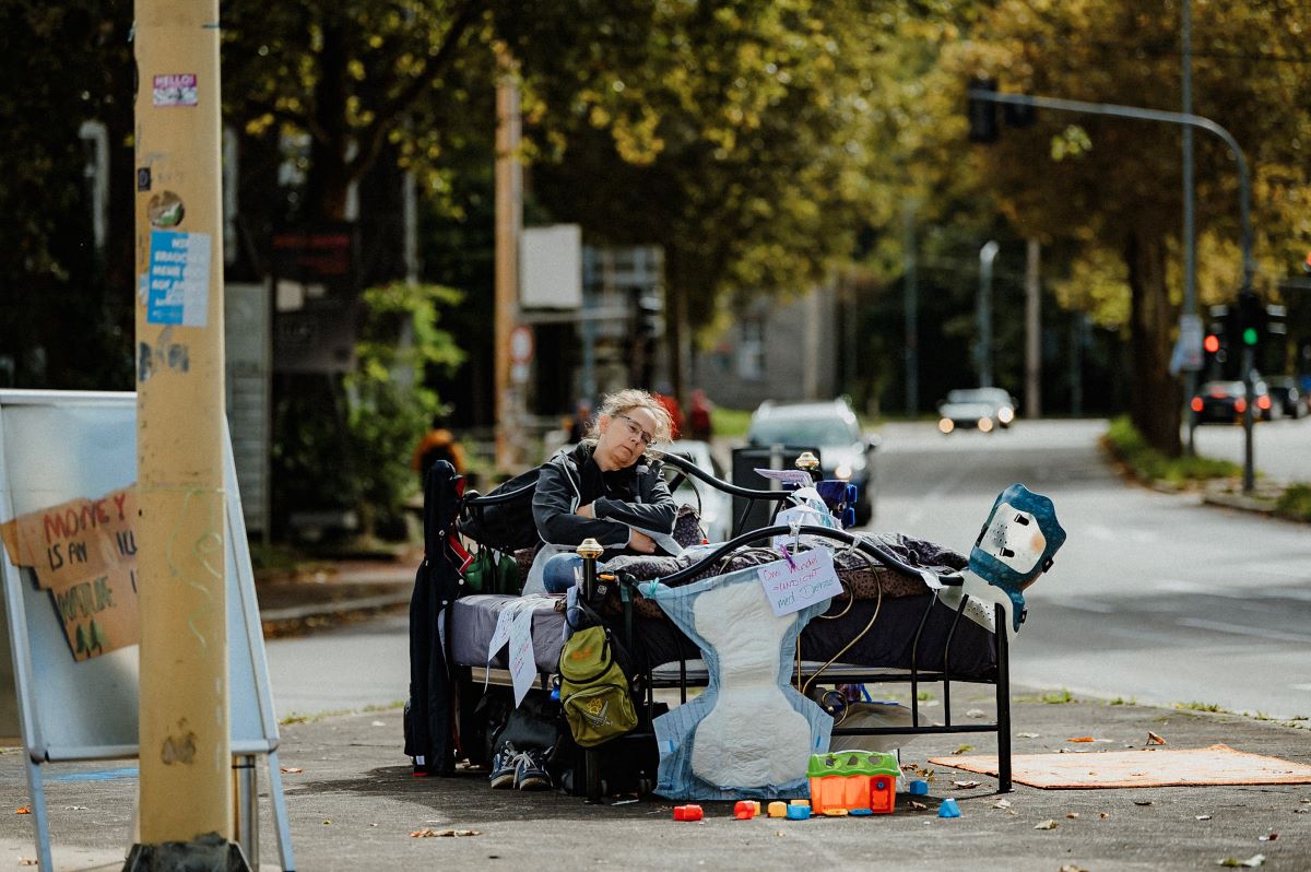 Burnoutbett © Sabine Watzko eine Person liegt in einem Bett, das auf einer Straßenkreuzung steht